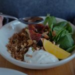 A vibrant brunch bowl with fruit, greens, and nuts for a nutritious meal.