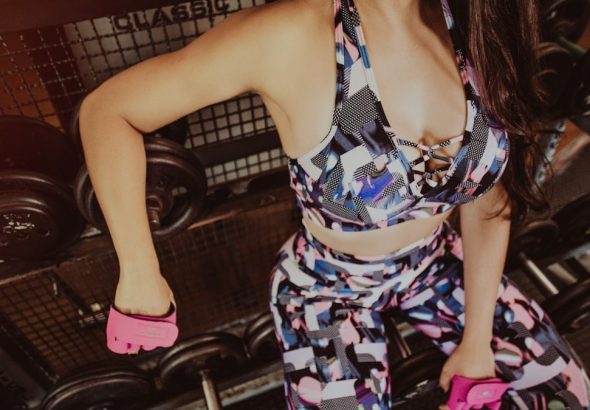 woman sitting on dumbbells on rack