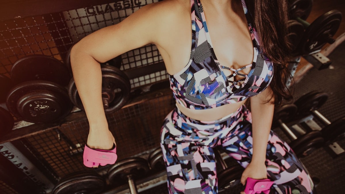woman sitting on dumbbells on rack